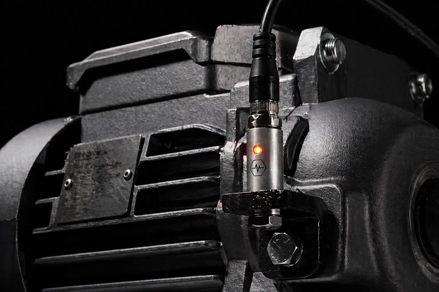 Vibration sensor with an orange status light mounted on an industrial motor